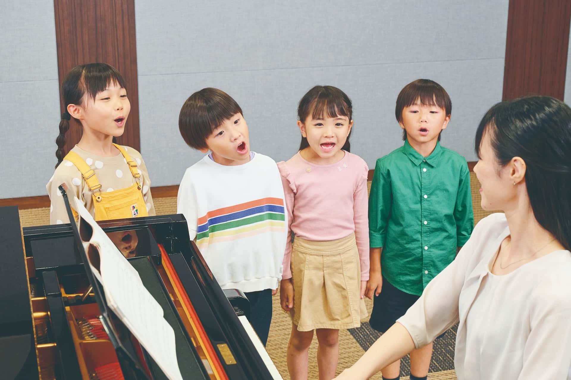 先生のピアノ伴奏に合わせて歌う生徒たちのレッスン風景