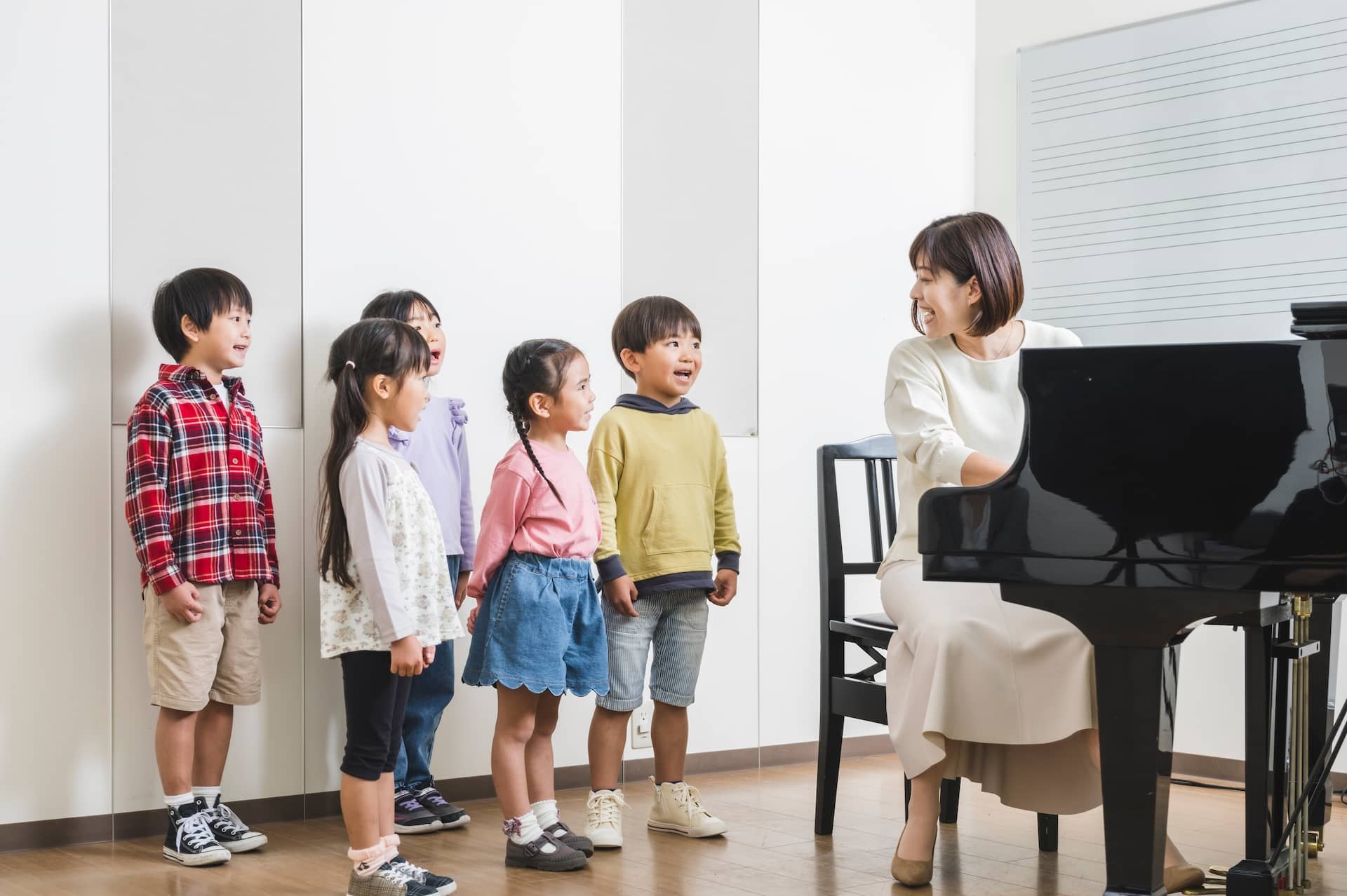 ピアノを演奏する先生を囲んで学ぶグループレッスンの様子